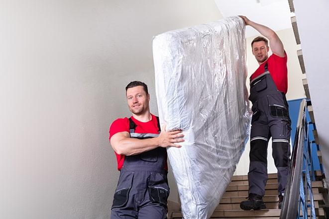 heavy lifting workers transporting a box spring out of a building in Bald Eagle